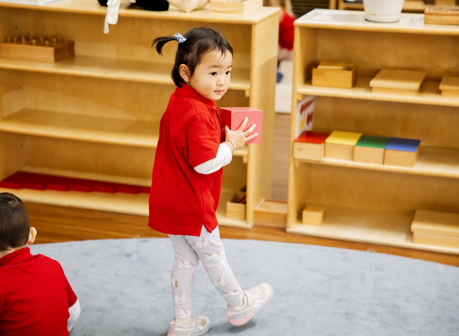 A child carrying a material to their workspace