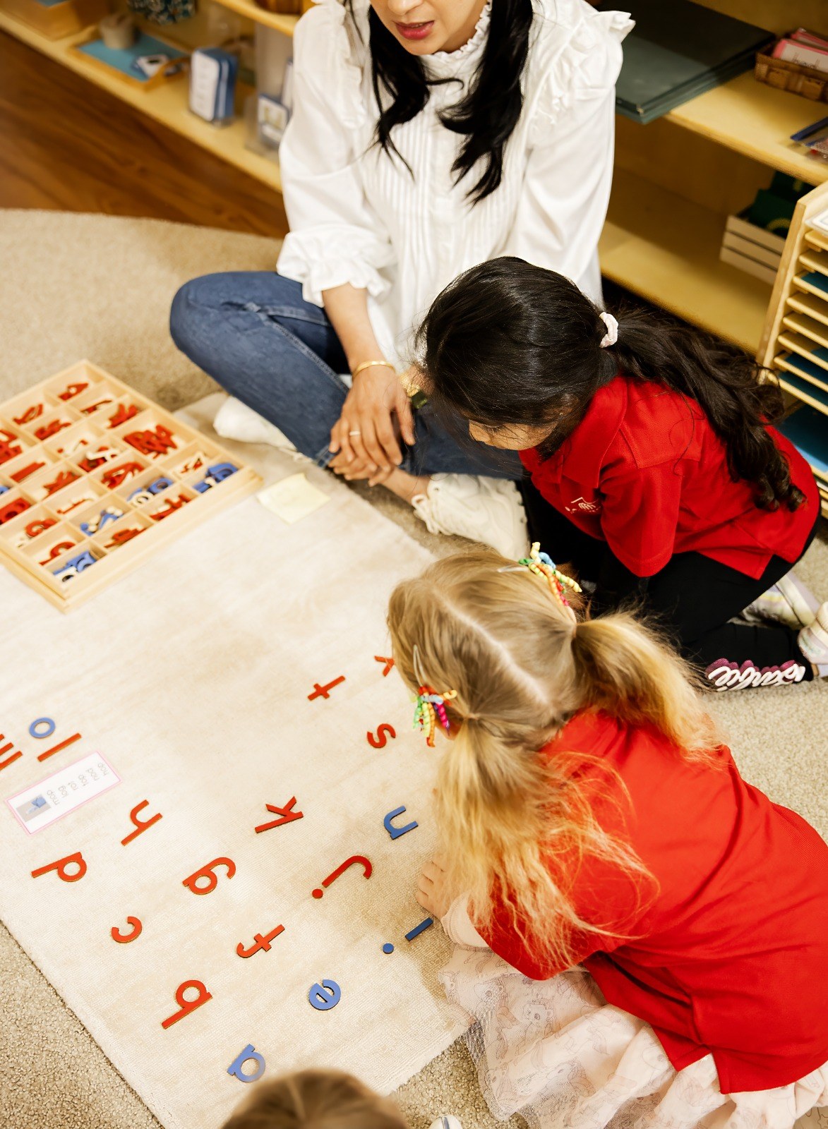 An educator seated with children working on the mat