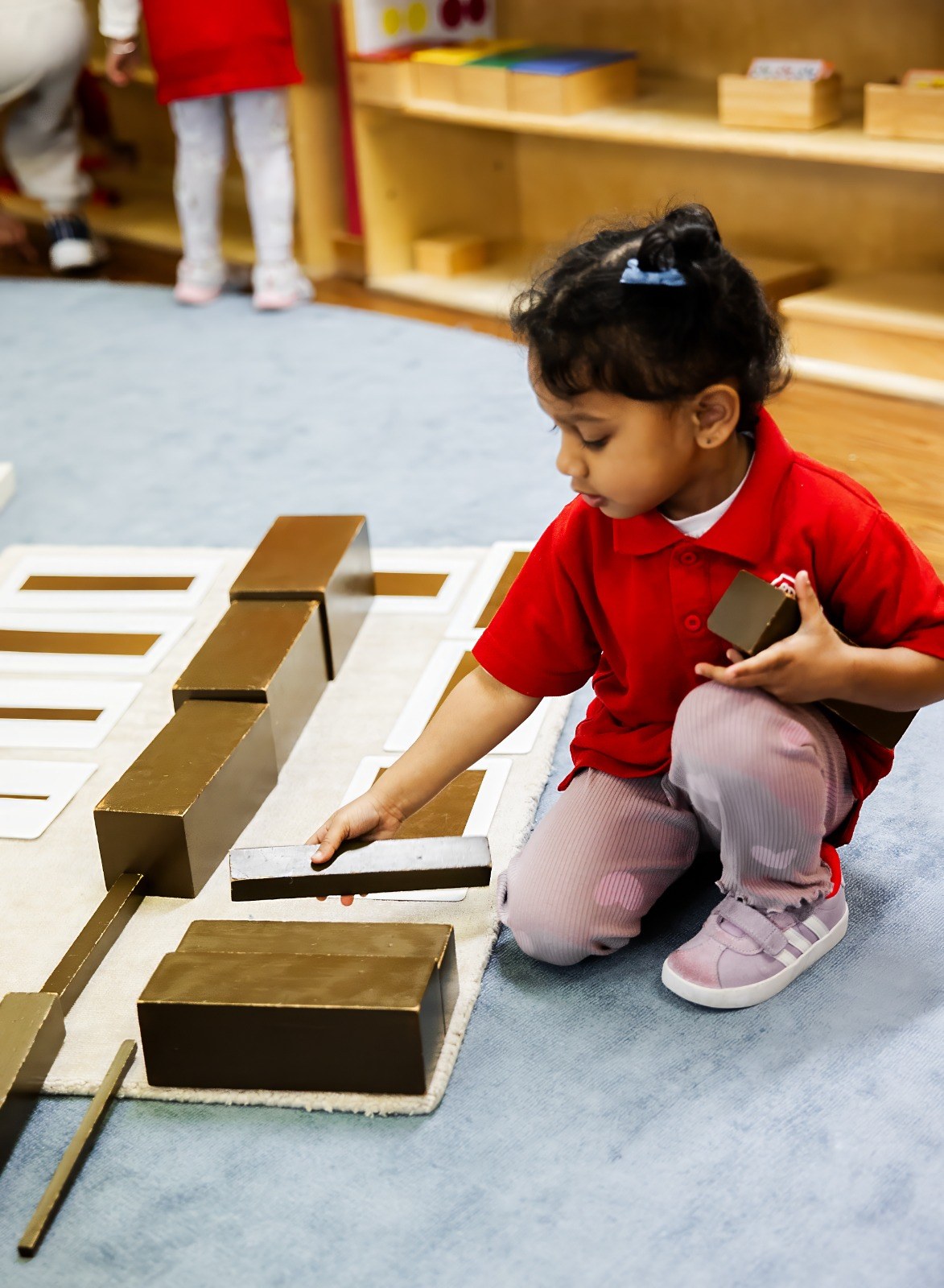 A child working with wooden stacking blocks on the floor