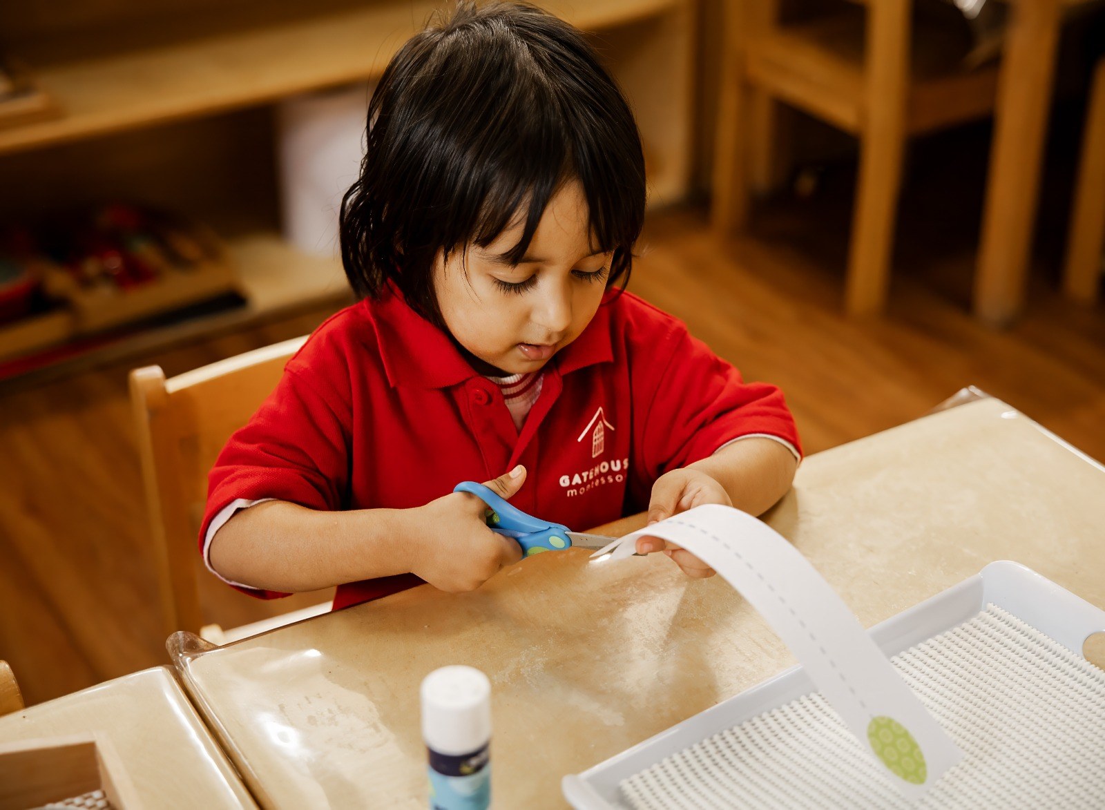 A child practising cutting skills with scissors at a table
