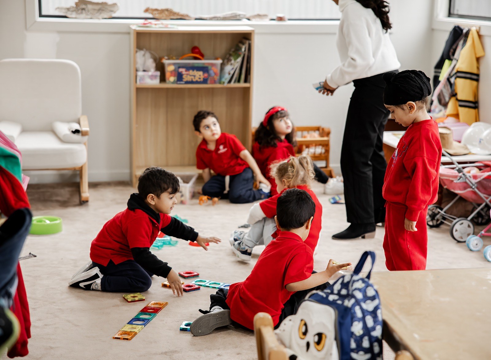 Children playing freely on the floor while an educator looks on