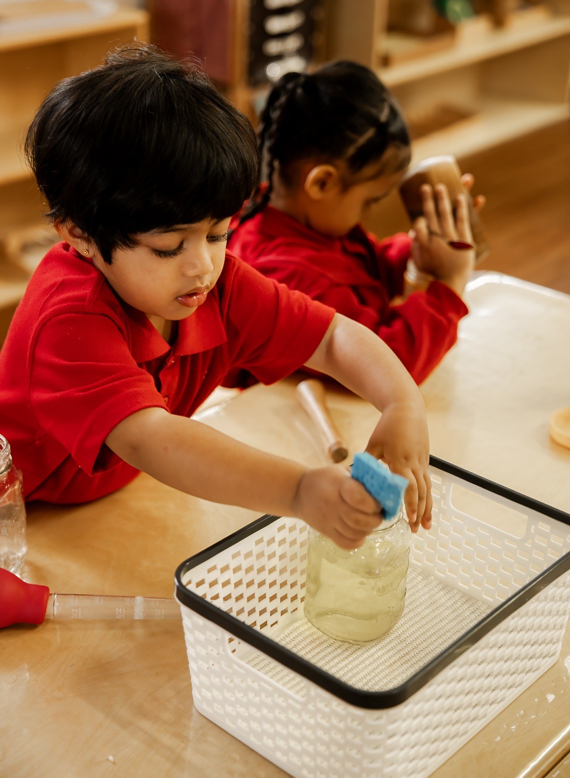Children pouring water together into a shared tray