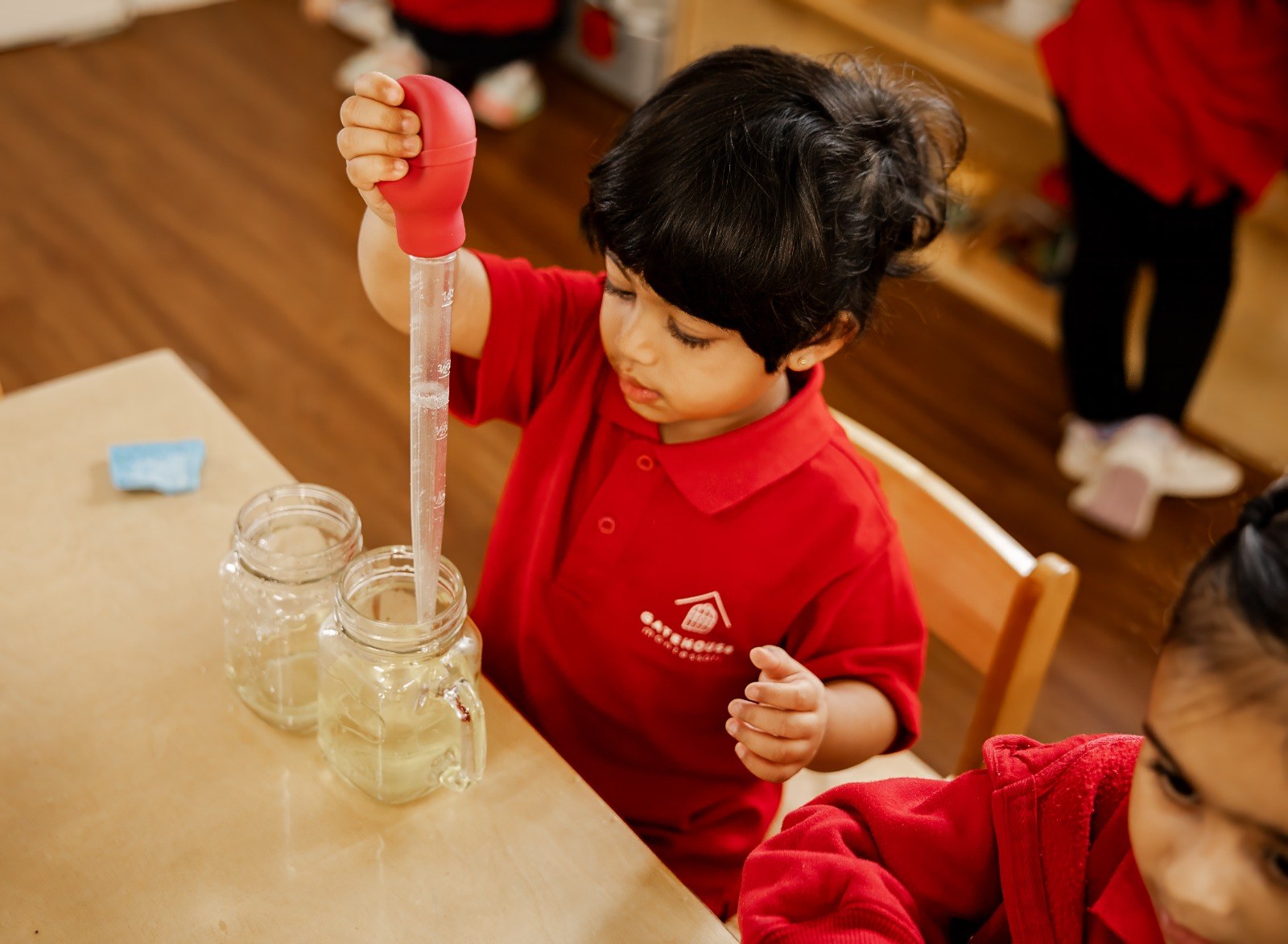 A child using a pipette to transfer coloured water