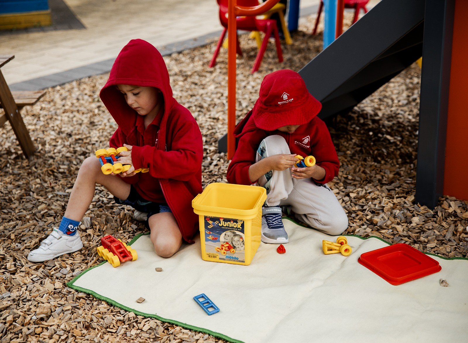 Two children playing with toy cars outdoors