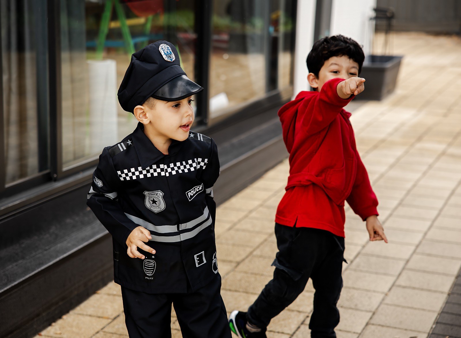 Children in imaginative play, one dressed as a police officer