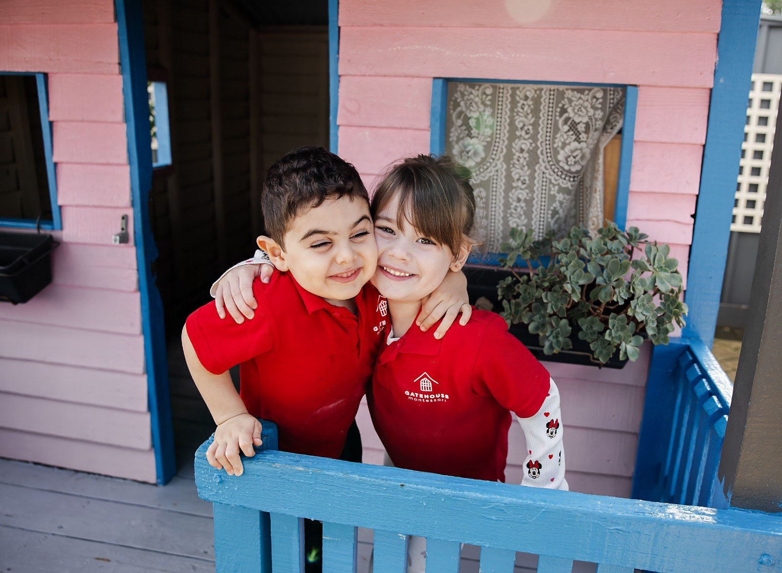 Two children hugging at the outdoor playhouse