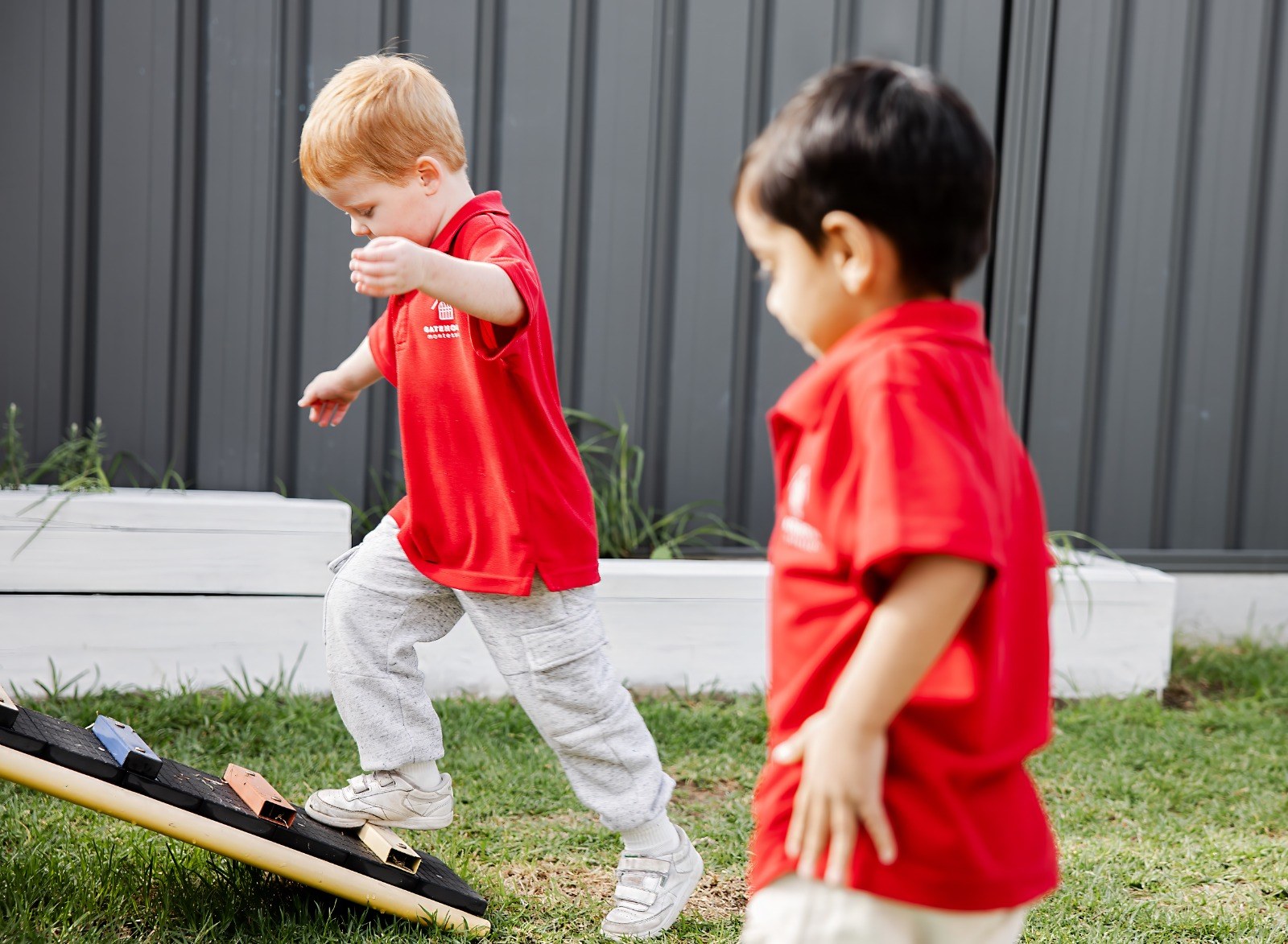 Two children balancing along an outdoor balance beam