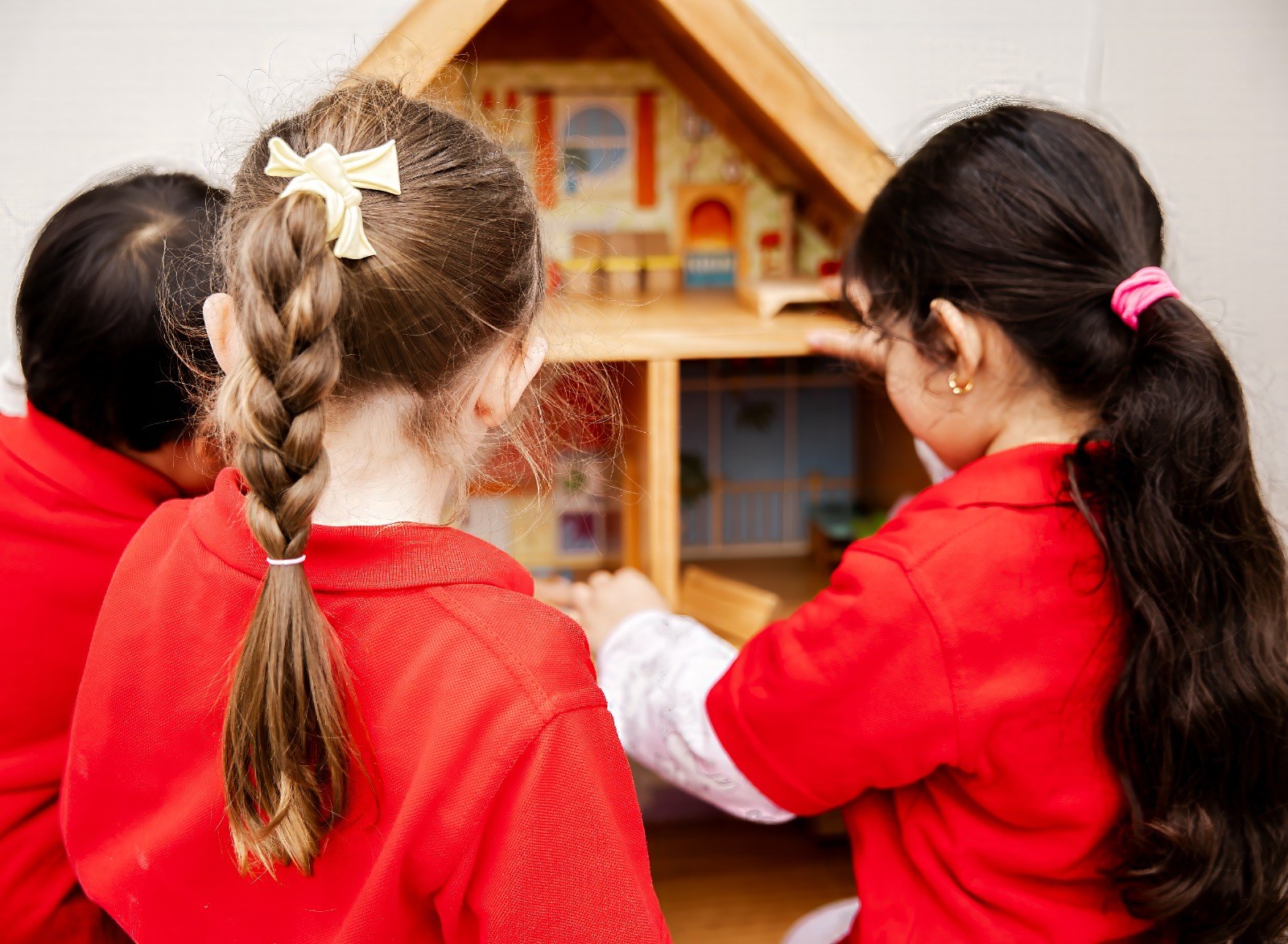 Two children playing together with a dollhouse