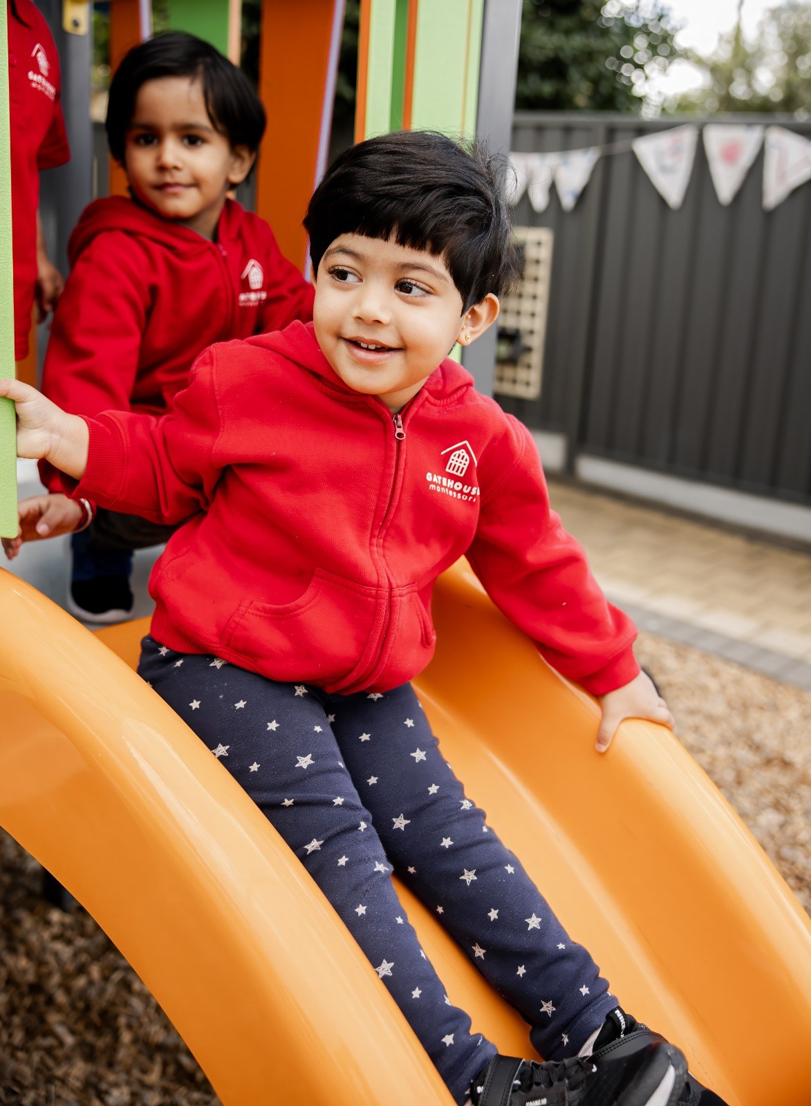 A child smiling while going down the outdoor slide
