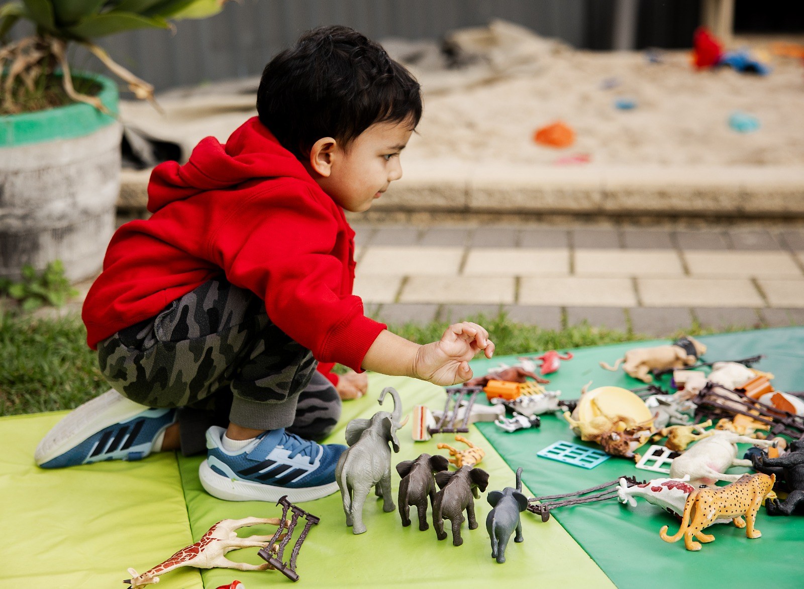 A child playing with animal figurines on a mat