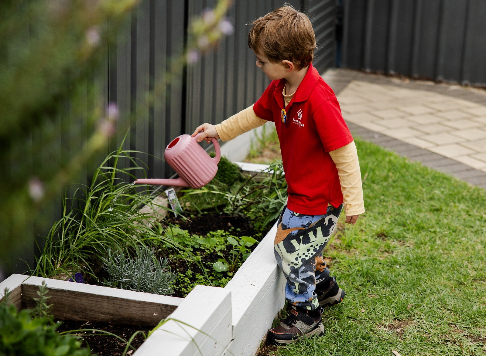 A child watering a garden bed with a watering can