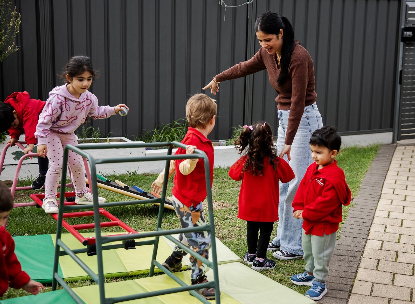 An educator with children on the outdoor climbing frame
