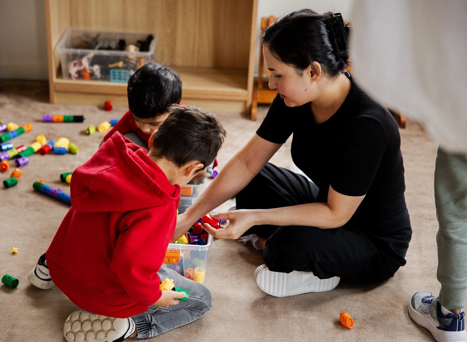 A child and educator building together with coloured blocks