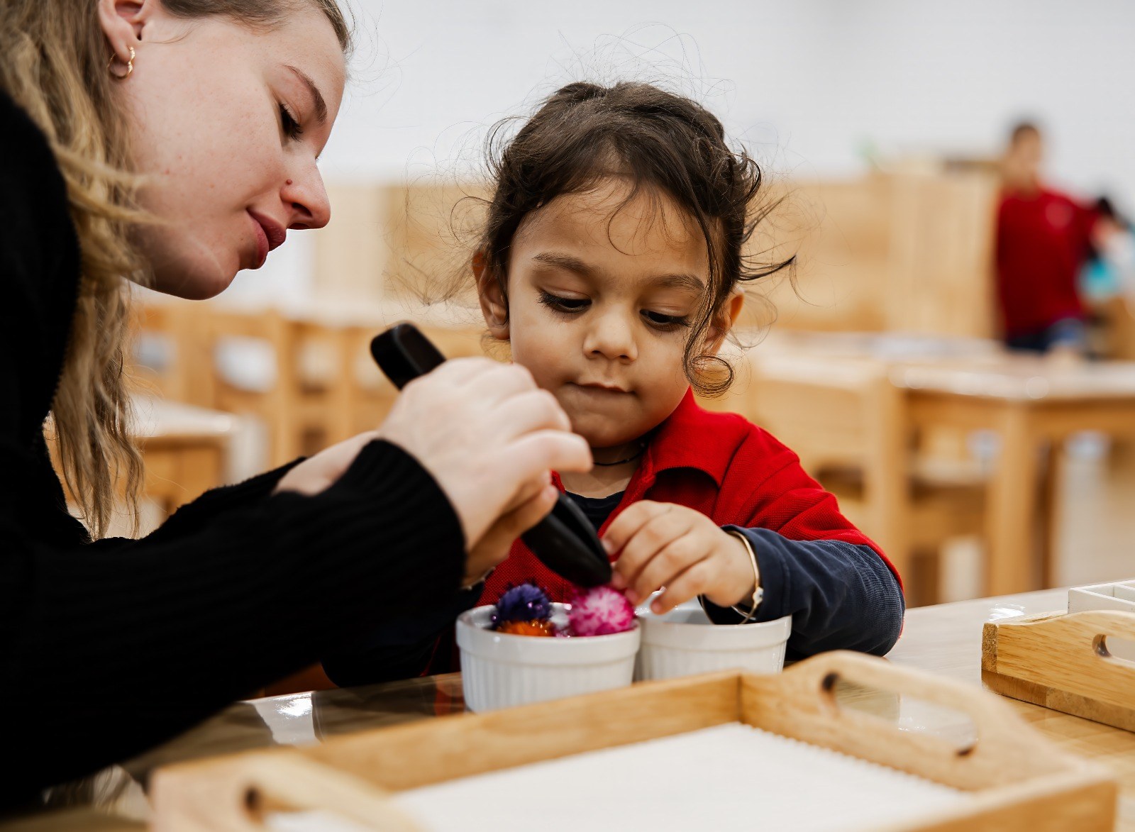 An educator helping a child with a craft activity