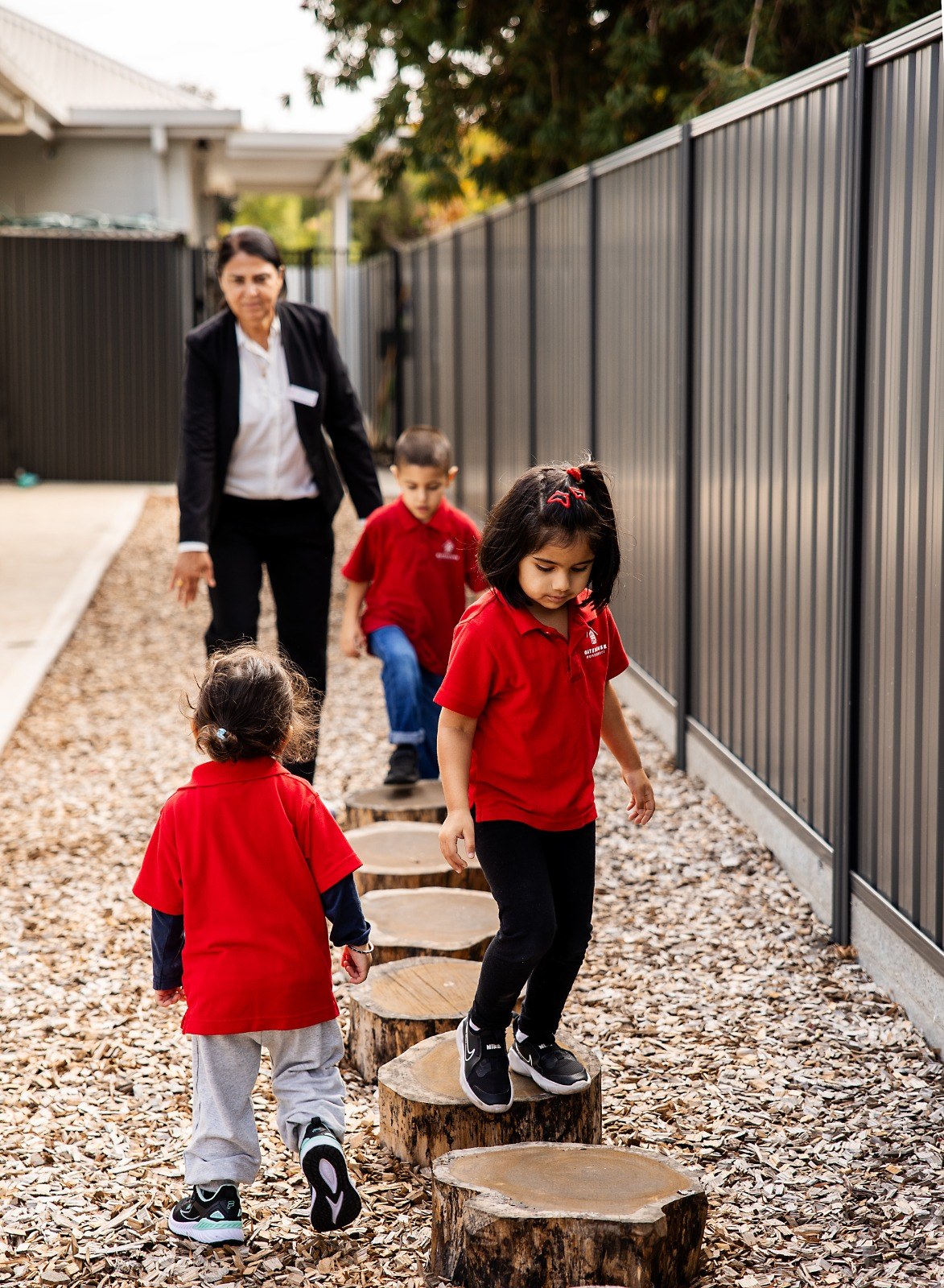 An educator walking outdoors with children along stepping stones