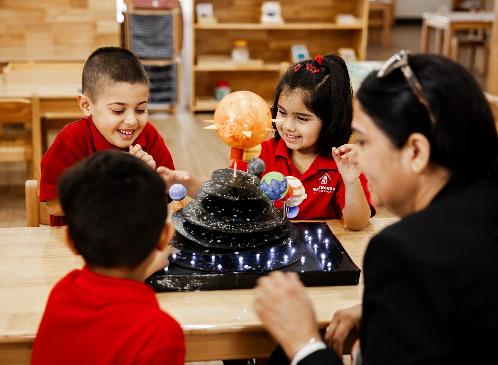 Children and a teacher exploring a solar system model together